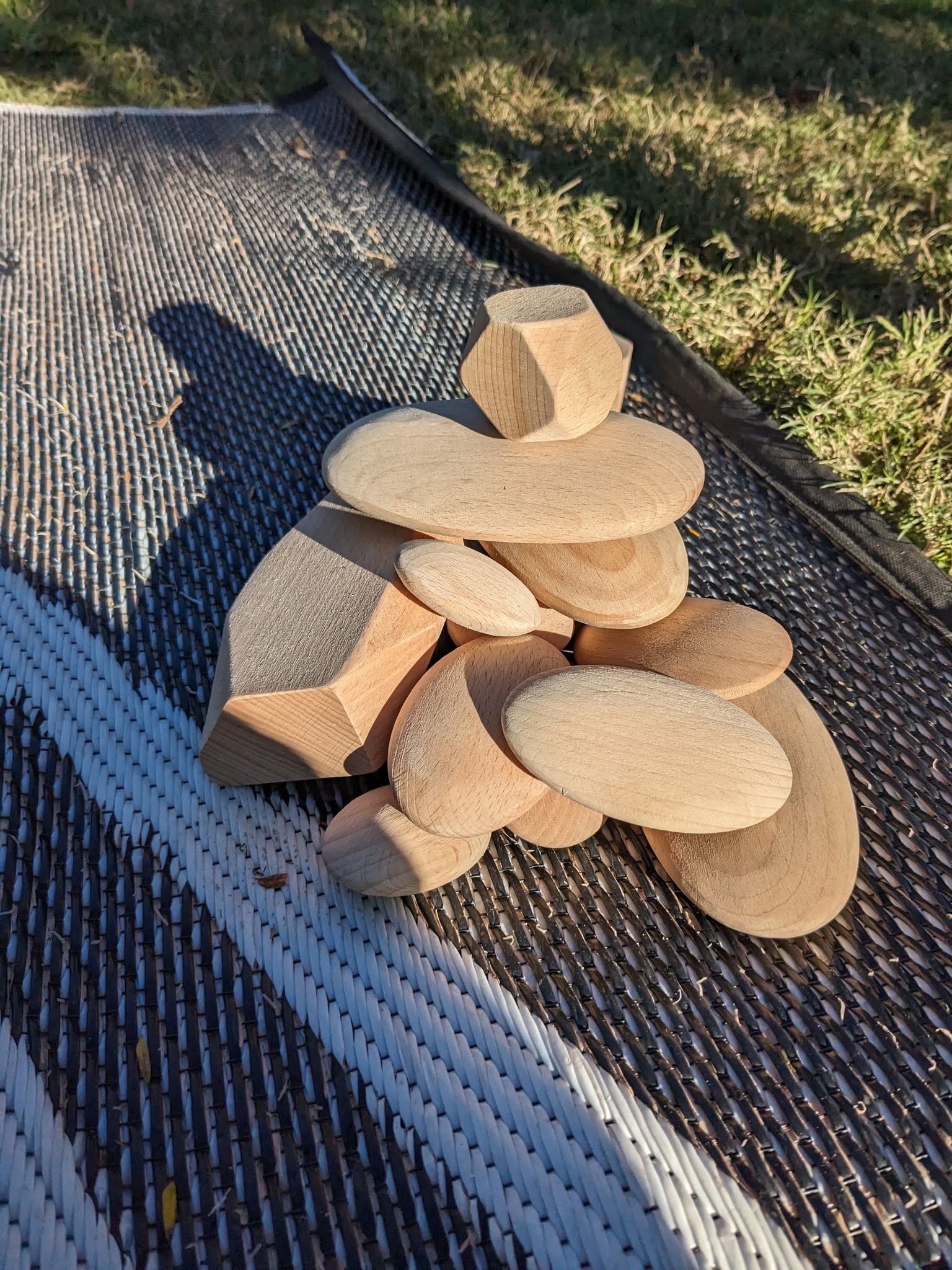 Smooth wooden blocks stacked and balanced on an outdoor mat